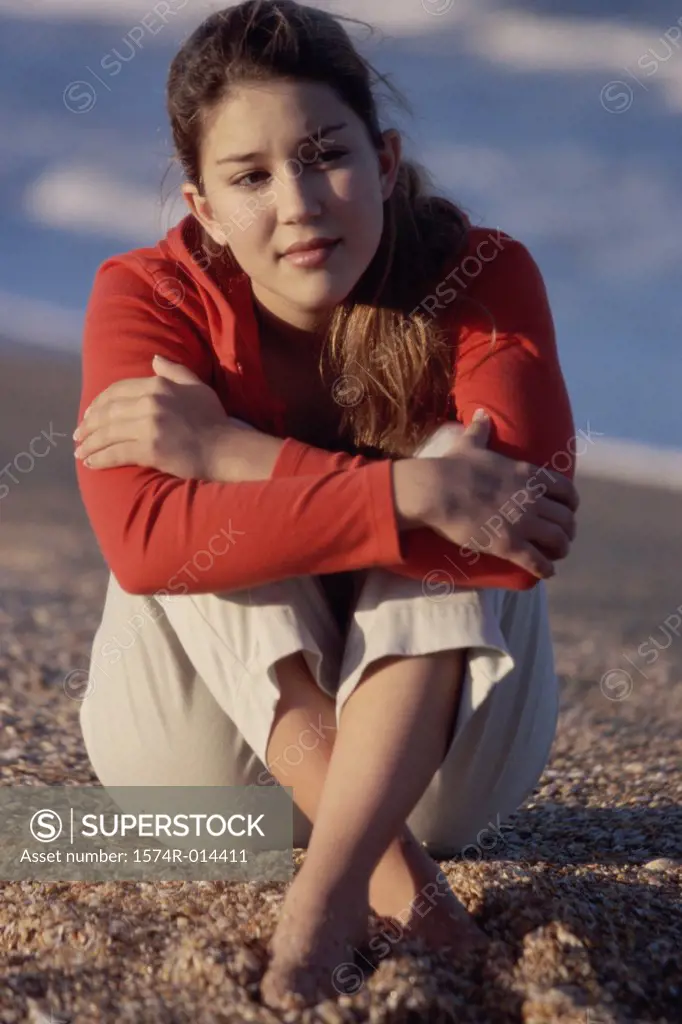 Teenage girl sitting on sand