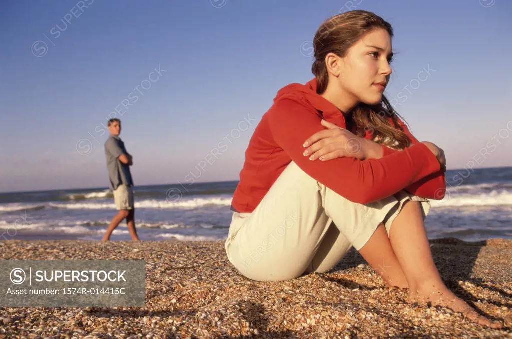 Side profile of a teenage girl sitting on the beach