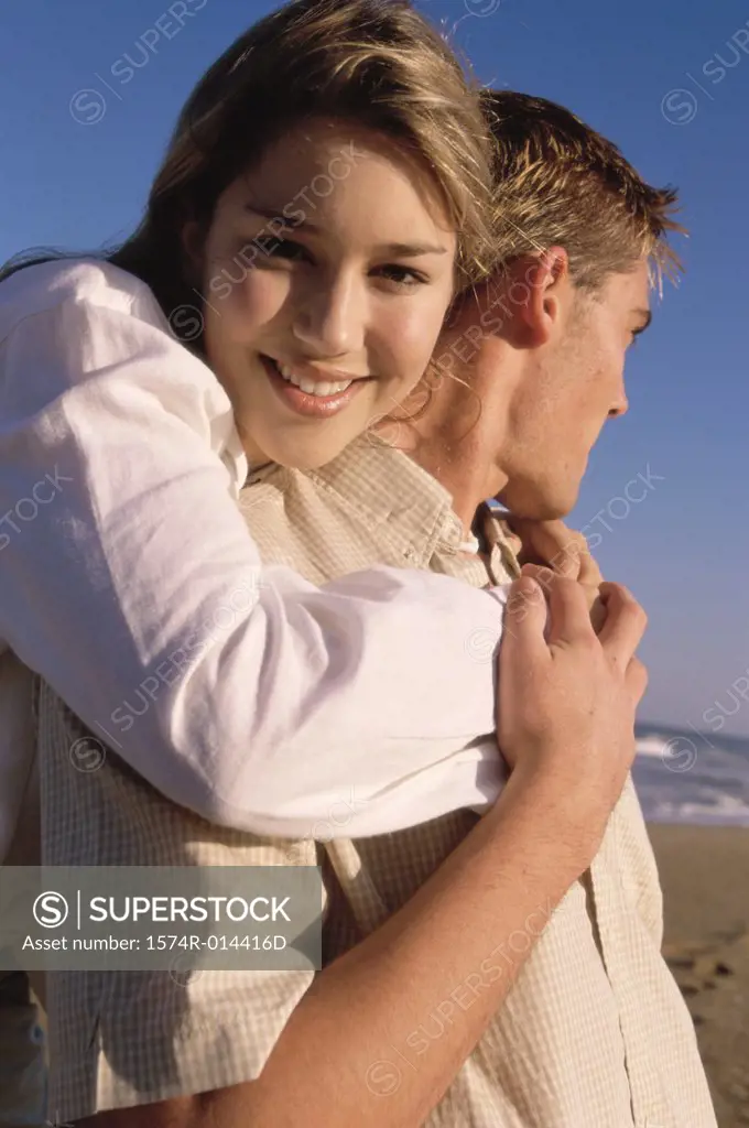 Portrait of a teenage girl hugging a young man