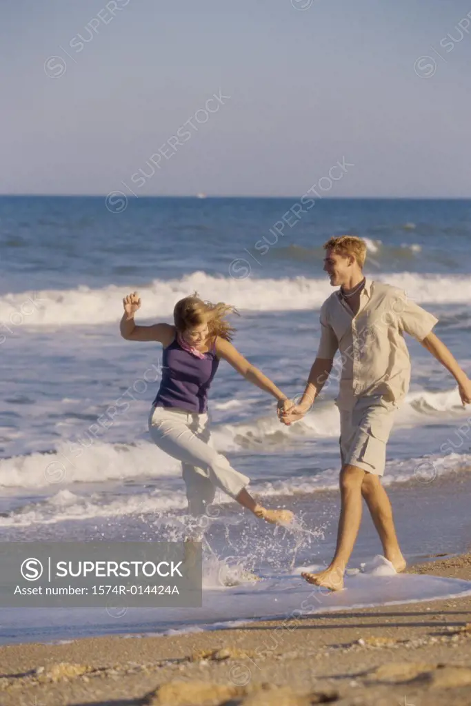 Teenage couple holding hands and walking on the beach