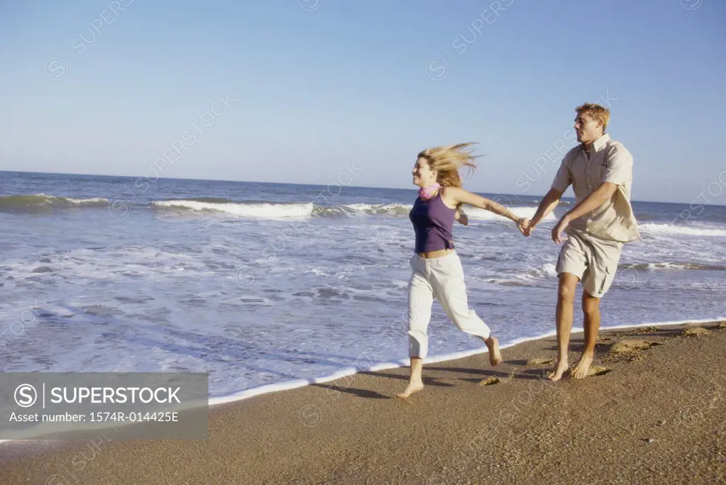 Teenage girl running with a young man on the beach