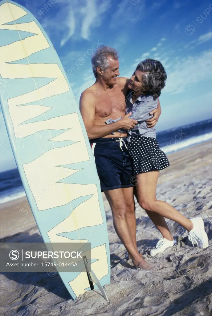 Senior couple at the beach near a surfboard