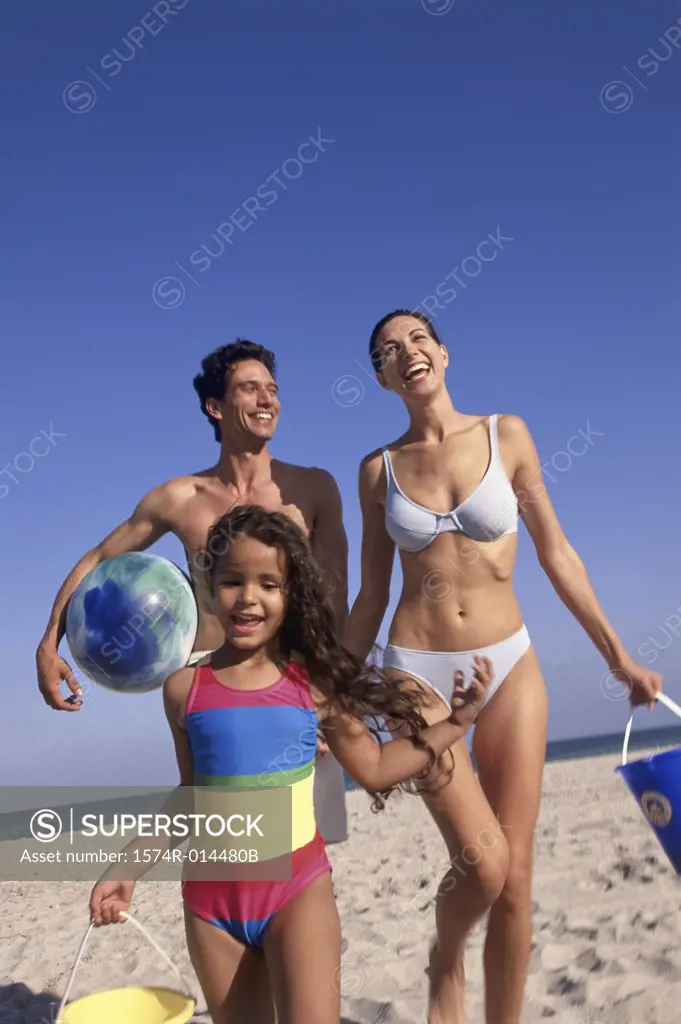 Low angle view of parents and their daughter standing on the beach