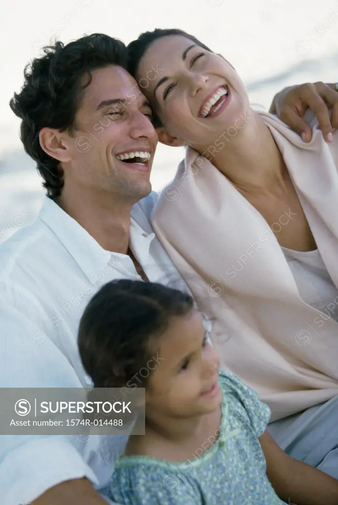 Close-up of parents and their daughter smiling on the beach