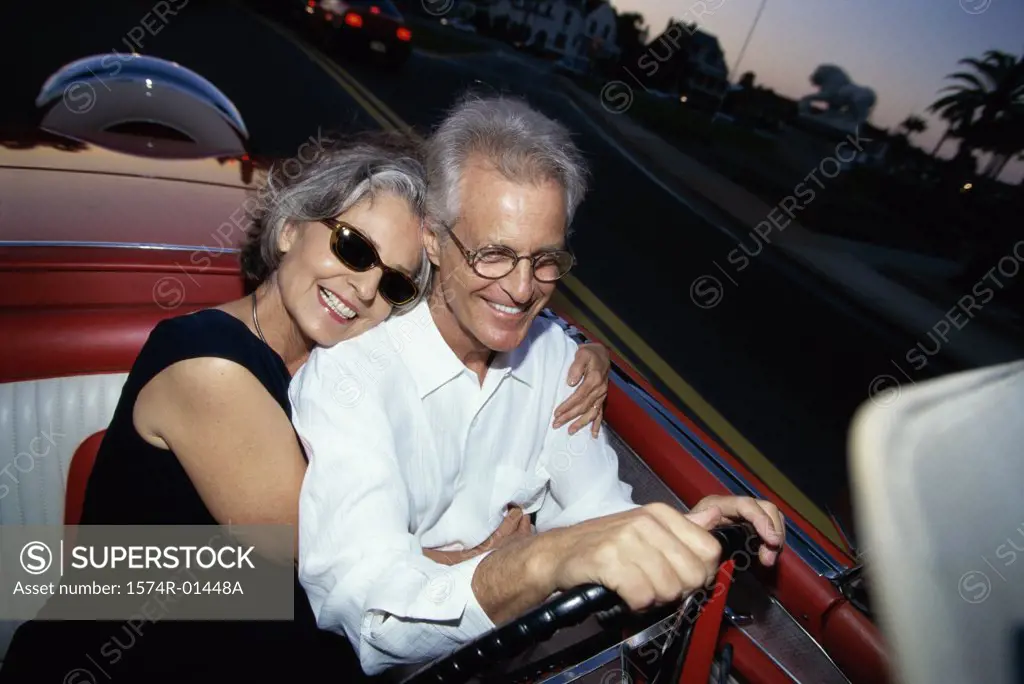 Senior couple driving a convertible car