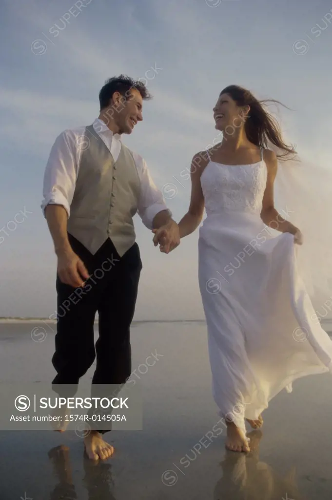 Low angle view of a newlywed couple walking on the beach
