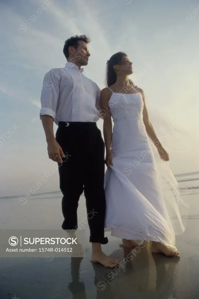Low angle view of a newlywed couple walking on the beach