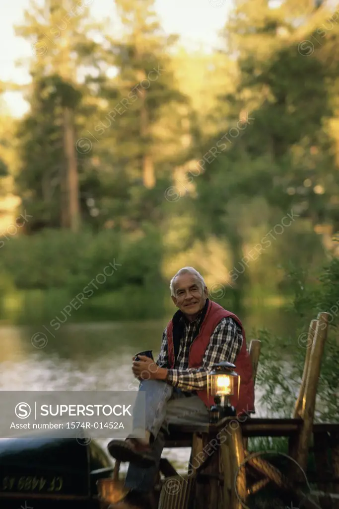 Portrait of a senior man sitting on a chair beside a lamp
