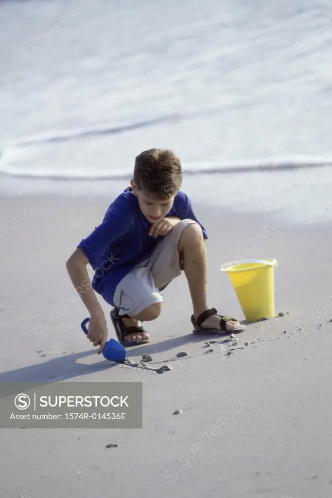 Boy digging sand with a shovel on the beach