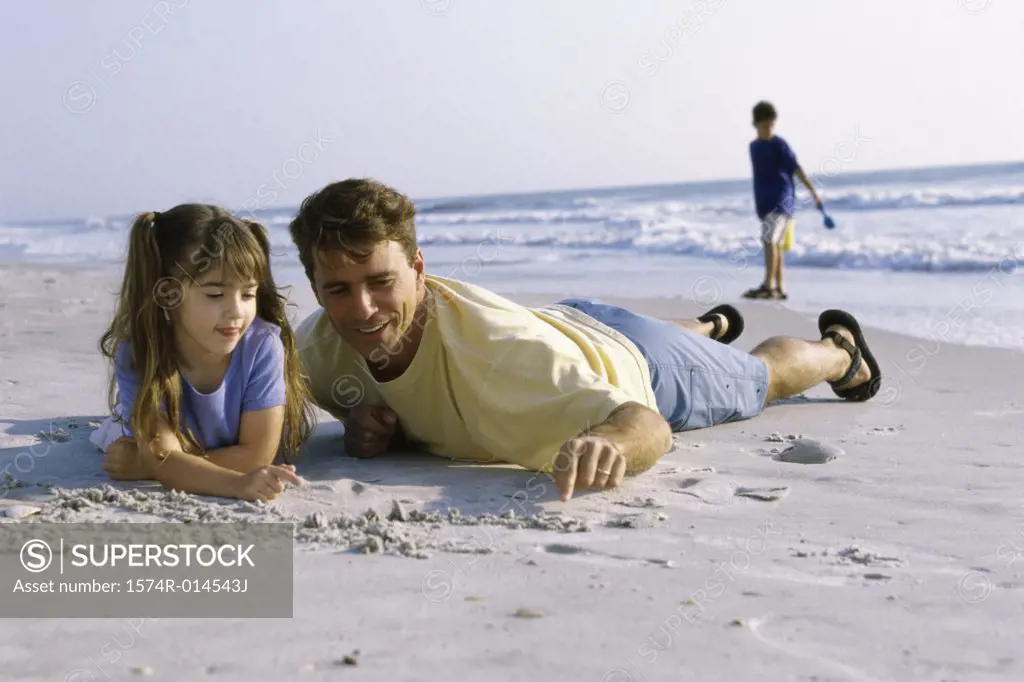 Father and his daughter writing in sand on the beach