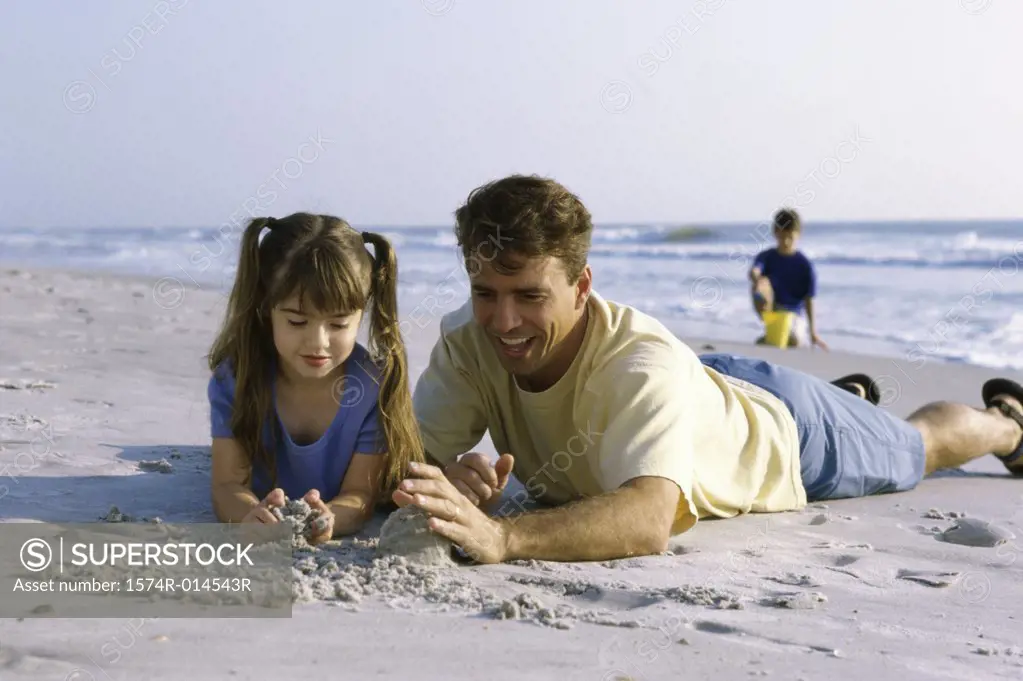 Father and his daughter making a sand castle on the beach