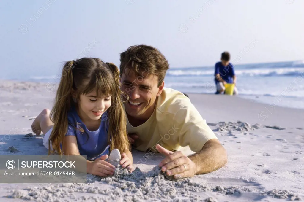 Close-up of a father with his daughter making a sand castle on the beach