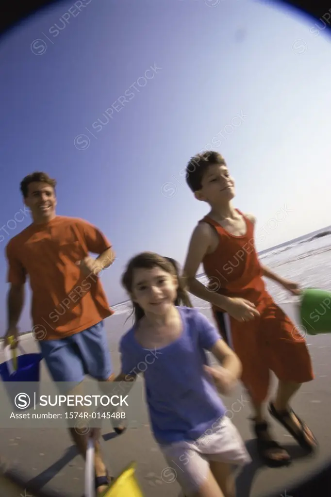 Father with his son and daughter running on the beach