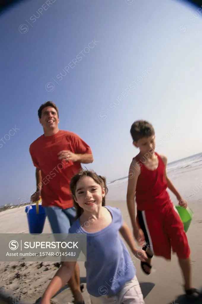 Father with his son and daughter running on the beach