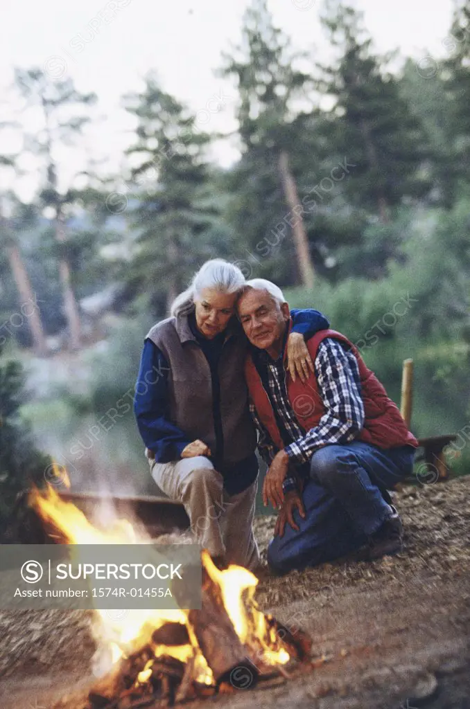 Senior couple together near a campfire in the woods