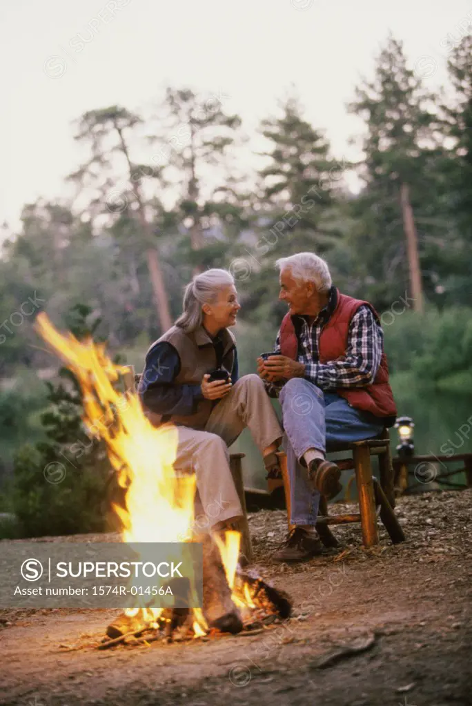 Senior couple sitting in front of a camp fire talking