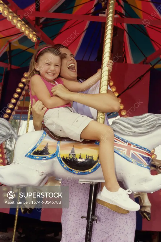 Low angle view of a mother with her daughter sitting on a carousel