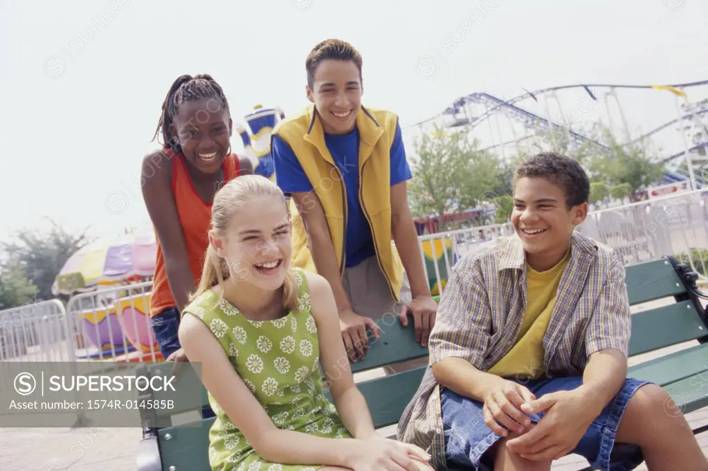 Two teenage couples sitting in an amusement park and smiling