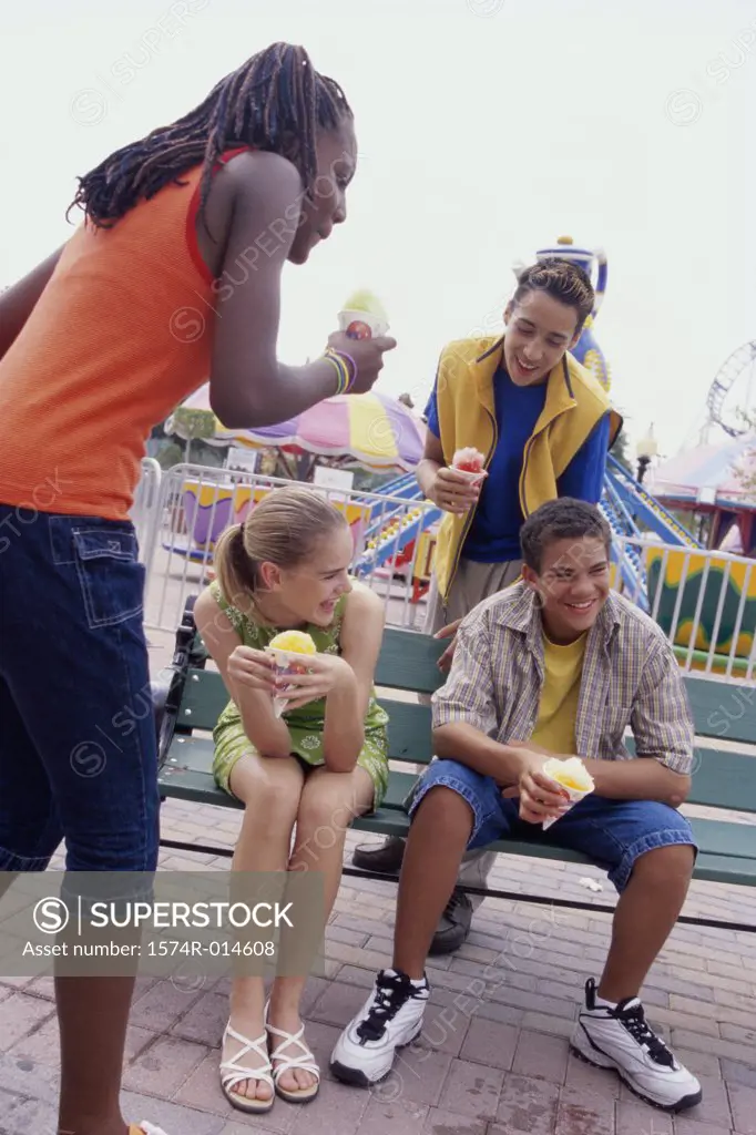 Two teenage boys and two teenage girls eating ice cream cones