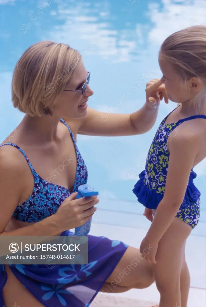 High angle view of a mother applying suntan lotion on her daughter
