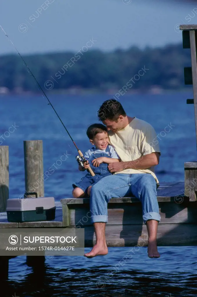 Father and son sitting on a pier fishing