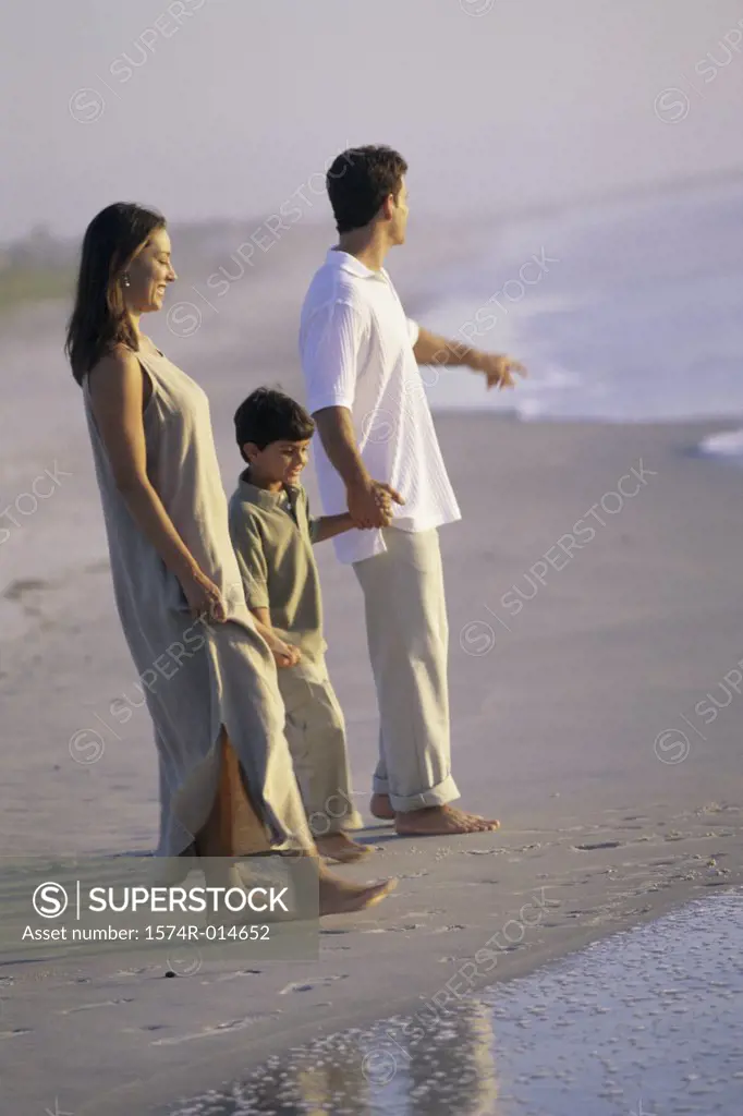 Side profile of parents and their son walking on the beach