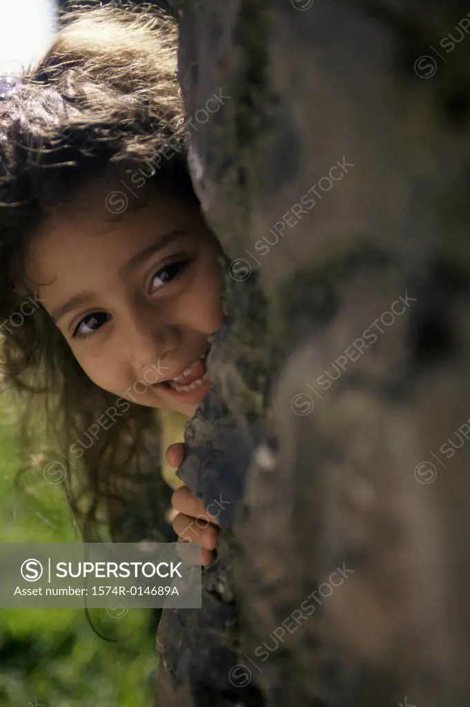 Portrait of a girl hiding behind a rock