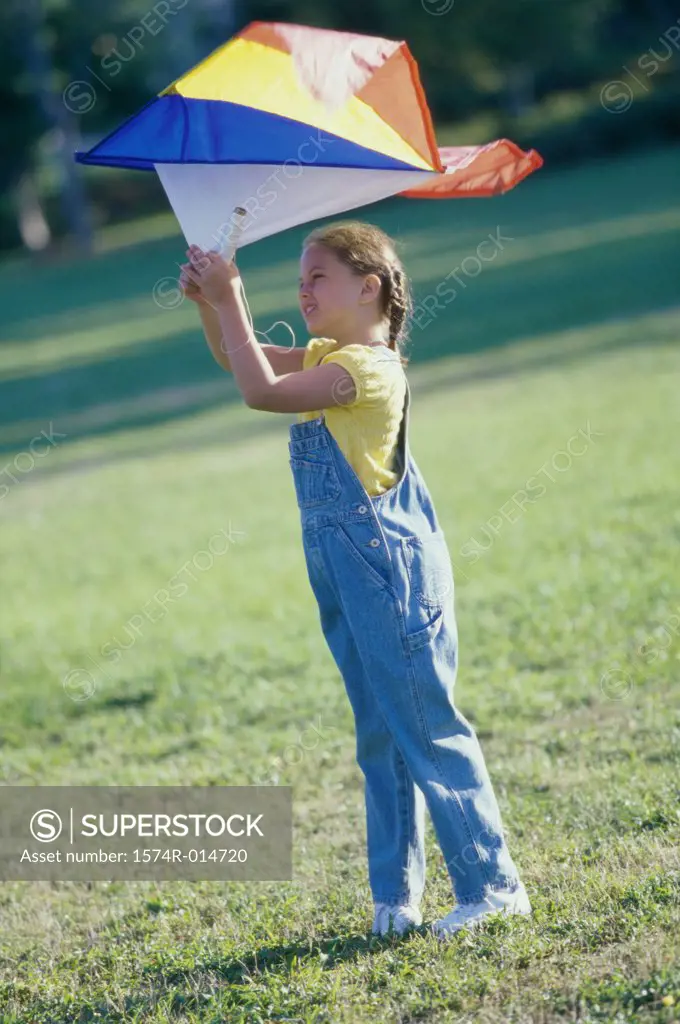 Side profile of a girl flying a kite on a lawn