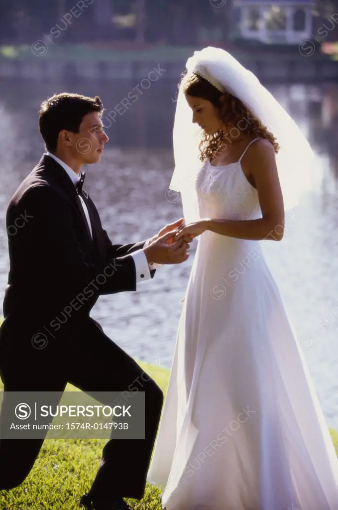 Side profile of a groom proposing to his bride near a lake