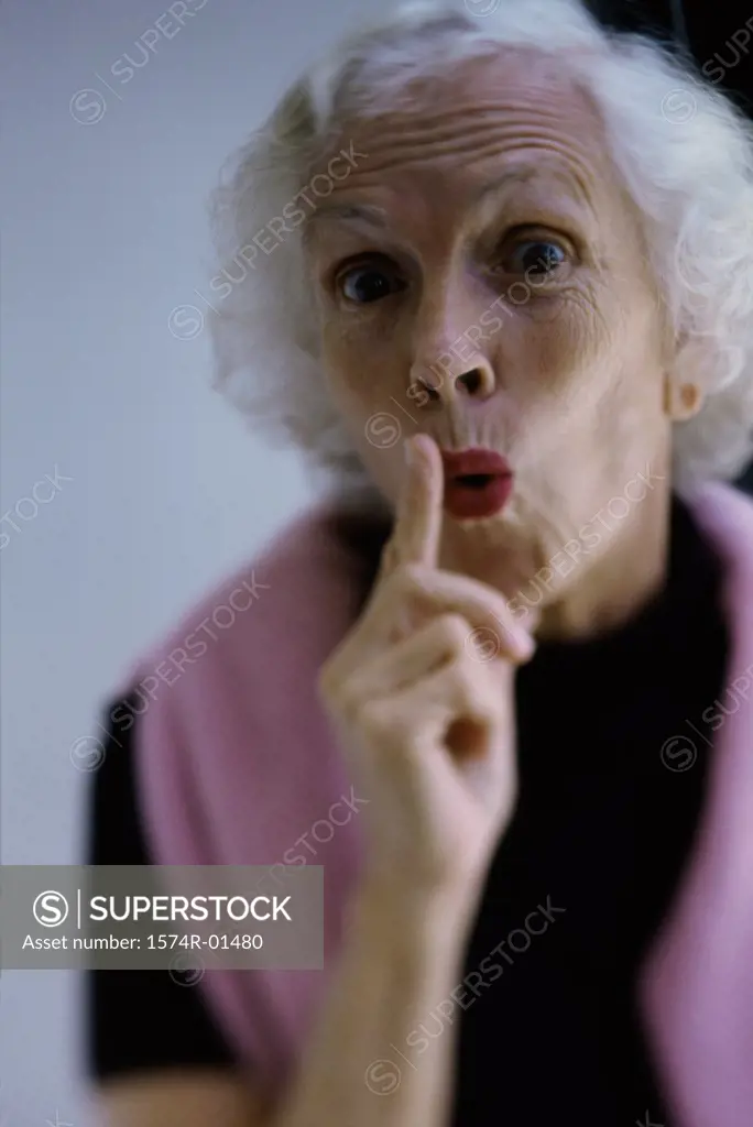 Portrait of a senior woman holding her finger up to her lips