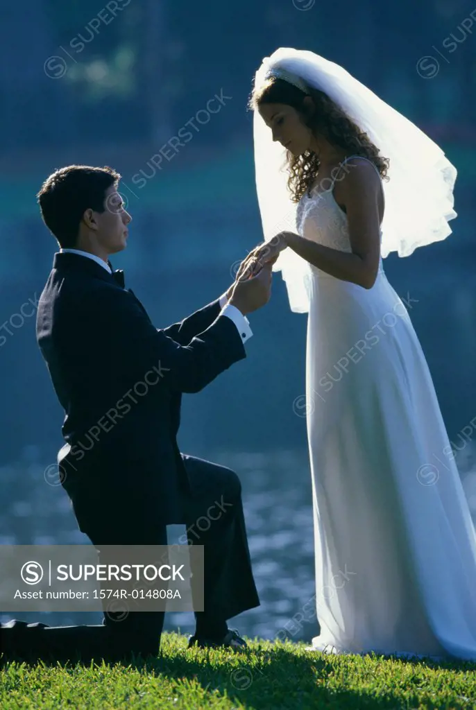 Side profile of a groom proposing to his bride near a lake