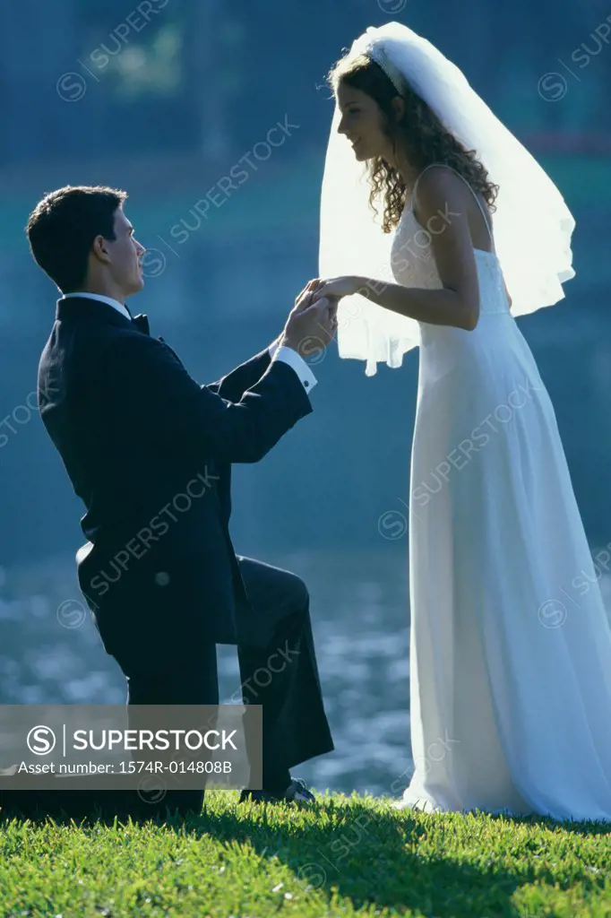 Side profile of a groom proposing to his bride near a lake