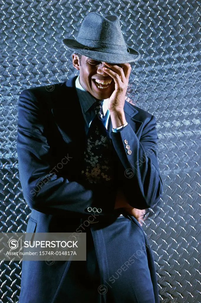 Businessman standing in front of a metallic wall laughing
