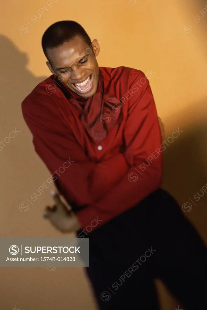 High angle view of a young man laughing with his arms crossed