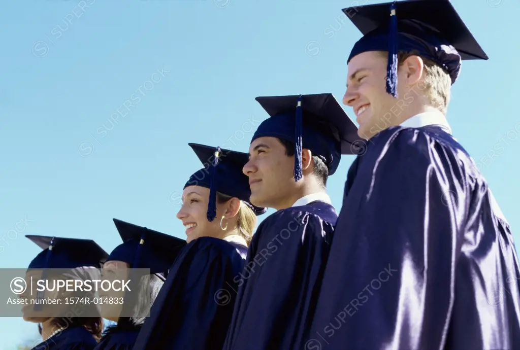 Low angle view of five teenage graduates standing in a row