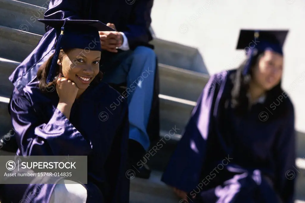 Portrait of a teenage graduate girl sitting on steps and smiling