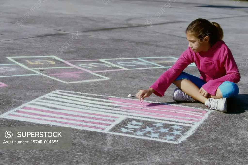High angle view of a girl drawing an American flag on the ground with chalk