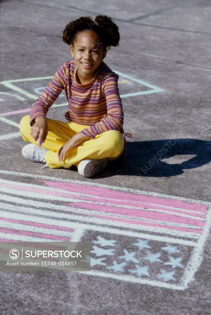 Portrait of a girl drawing an American flag on the ground with chalk