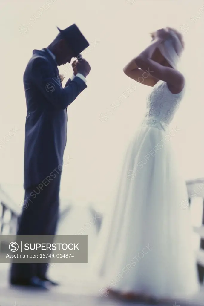 Side profile of a newlywed couple adjusting their hats