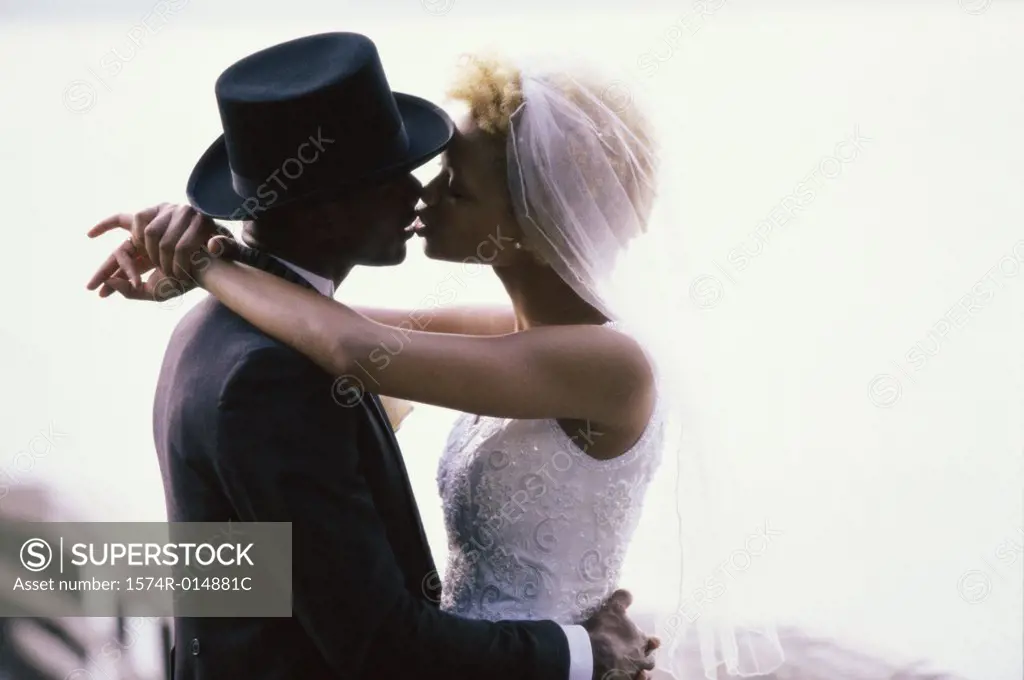 Side profile of a newlywed couple kissing each other