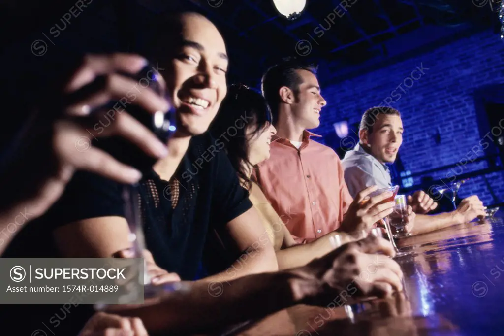 Low angle view of four people at a bar smiling