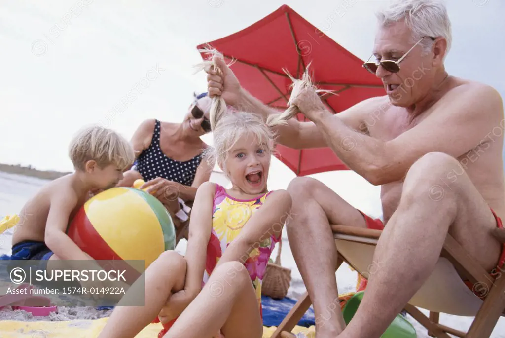 Close-up of a grandfather pulling his granddaughter's hair on the beach