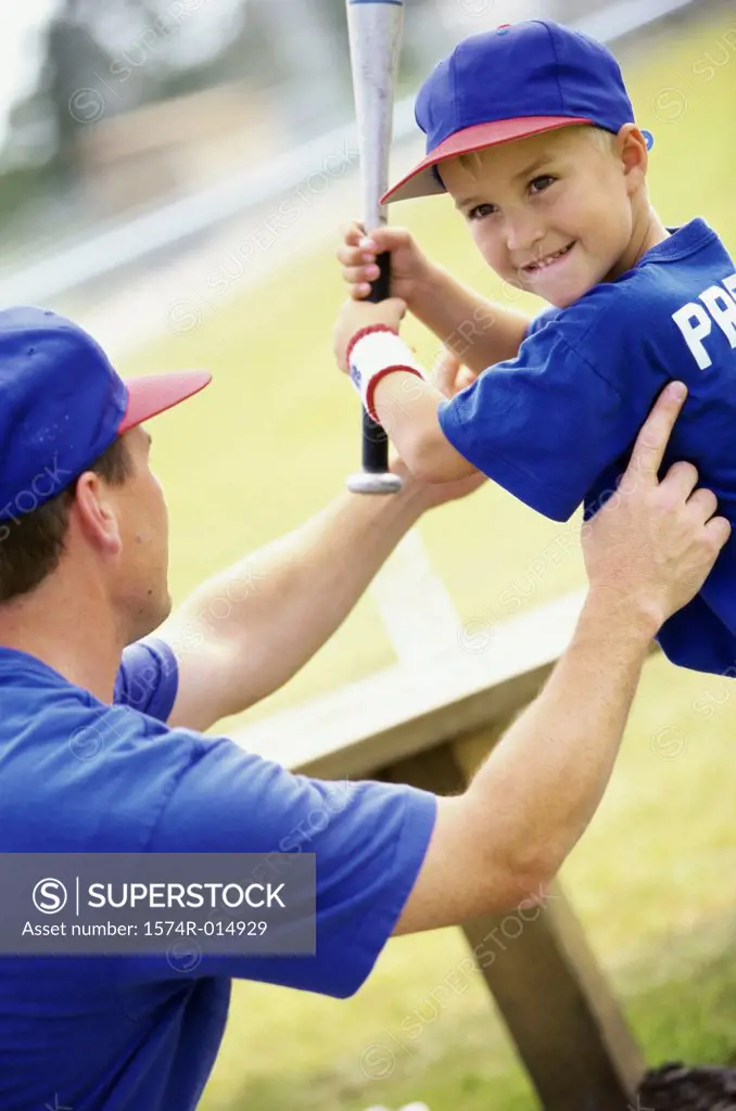 Side profile of a coach teaching a boy to play baseball