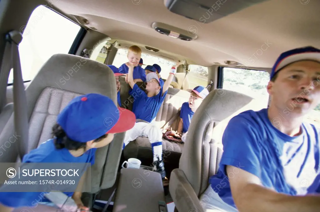 Baseball players sitting with their coach in a van