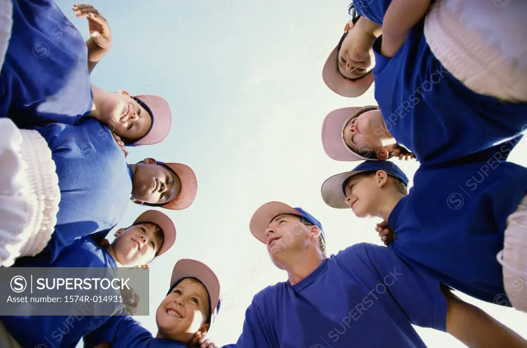 Low angle view of baseball players standing in a huddle with their coach