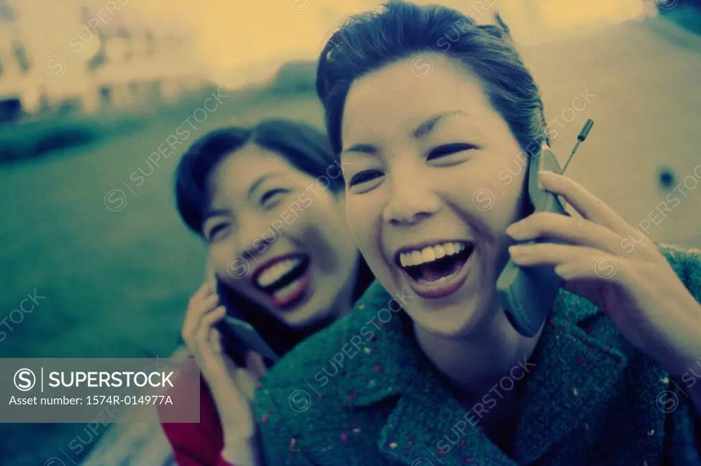 Two young women talking on their mobile phones