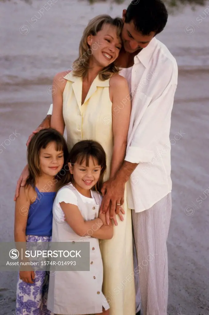 Parents and their two daughters standing on the beach