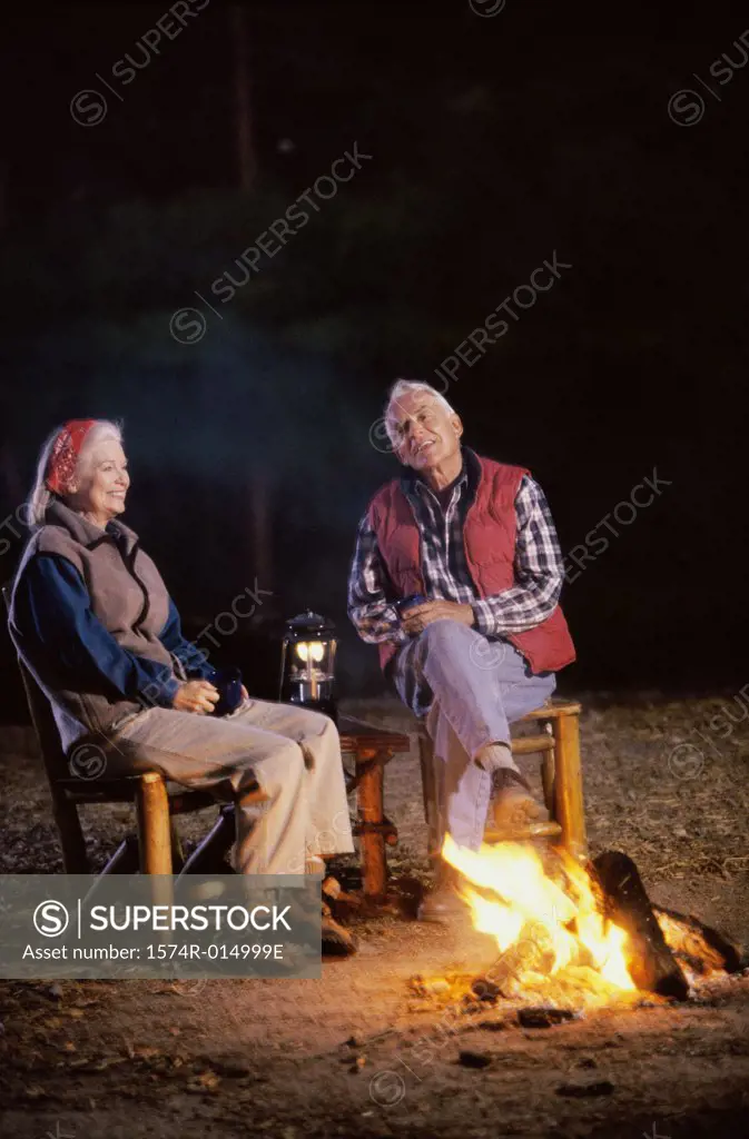 Senior couple sitting near a campfire talking to each other