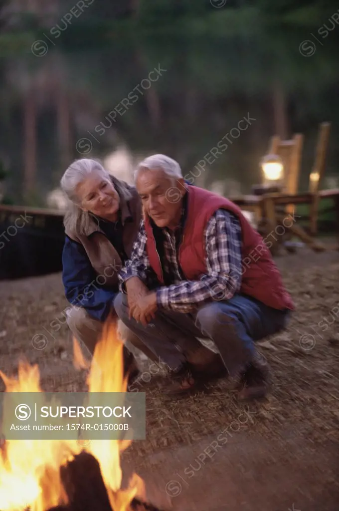 Senior couple crouching and singing near a campfire