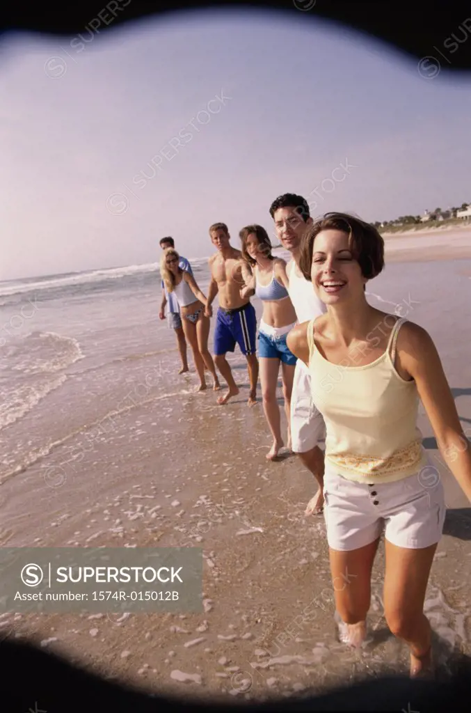 Three young couples holding hands walking on the beach